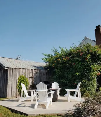 three white chairs and a table in a yard at The Wild Rose - Cozy PEC Rental in Picton in Picton