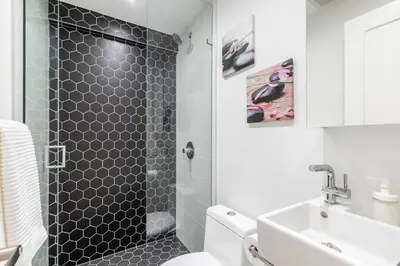a bathroom with a shower with a toilet and a sink at Westend Suites - Beautifully Furnished 3BR Apartment Close to High Park in Toronto