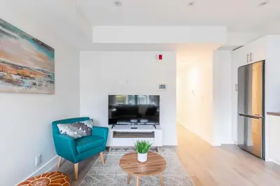a living room with a blue chair and a tv at Westend Suites - Beautifully Furnished 3BR Apartment Close to High Park in Toronto