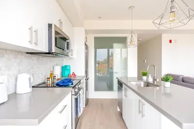 a kitchen with white cabinets and a sink at Westend Suites - Contemporary 3BR with Natural Light High Park North in Toronto