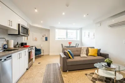 a living room with a couch and a kitchen at Westend Suites - Modern 1BR Apartment - 8min walk to High Park in Toronto