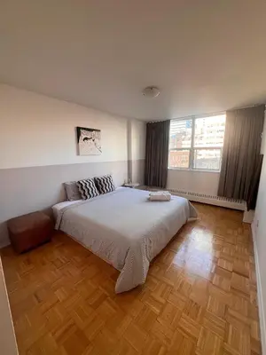 a bedroom with a large bed and a wooden floor at The Charming Downtown Stop in Toronto
