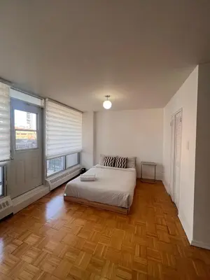 a bedroom with a bed and two windows at The Charming Downtown Stop in Toronto
