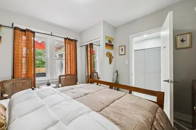 a bedroom with a large bed and two windows at Ora's Place BNB in Niagara Falls
