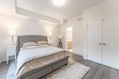 a white bedroom with a large bed and a white closet at Luxury Townhouse in Vaughan in Vaughan