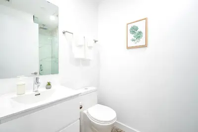 a white bathroom with a toilet and a sink at Chic 2BR Basement Suite 2BR Toronto Getaway near Downtown - The Roland in Toronto