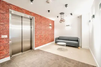 a lobby with a black couch and a brick wall at Chic 2BR Basement Suite 2BR Toronto Getaway near Downtown - The Roland in Toronto