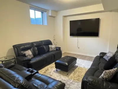 a living room with black leather furniture and a flat screen tv at Modern Luxury Basement Suite in Oakville