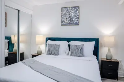 a bedroom with a large white bed with two lamps at 2 Bed 2 Bath Bunglow in Mississauga Yyz PortCredit in Mississauga