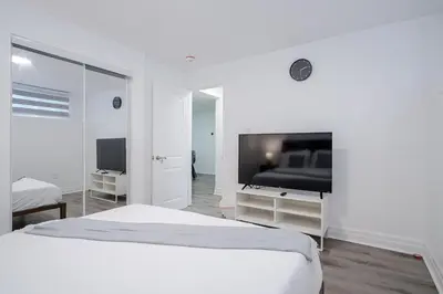 a white bedroom with a bed and a flat screen tv at 2 Bed 2 Bath Bunglow in Mississauga Yyz PortCredit in Mississauga