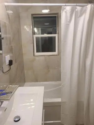 a white bathroom with a tub and a window at 2 Bedroom house in East-York in Toronto