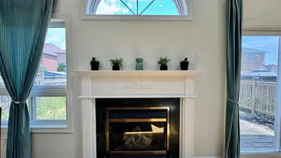 a fireplace in a living room with two windows at Spacious 4BD Oasis with Sauna in Mississauga