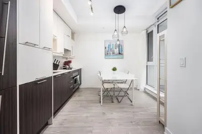 a kitchen with white cabinets and a table in it at Top Graded Metropolitan Suite with Free Parking in Toronto