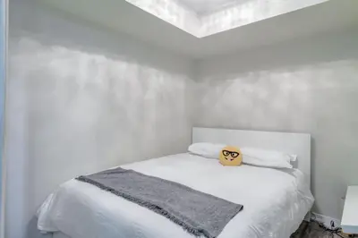 a white bedroom with a bed with a pillow on it at Chic 1BR plus Den Condo with Fast WiFi and Free Parking in Toronto