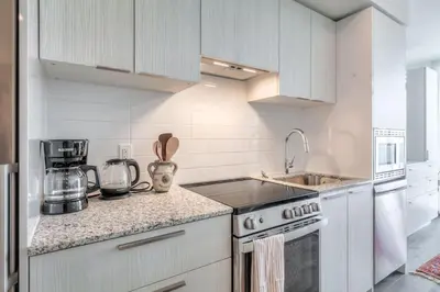a kitchen with white cabinets and a stove top oven at Downtown 1BR City Stay with Balcony and Fast Wi-Fi in Toronto