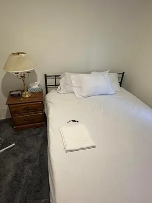 a white bed with a white towel on top of it at Goldwin's Place in Toronto