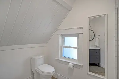 a white bathroom with a toilet and a window at The Dove Loft Near DT & Hospital in Peterborough