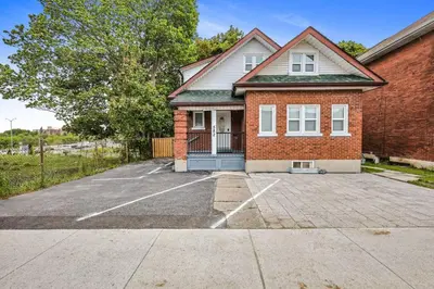an empty parking lot in front of a brick house at Comfy 2BR Apt near Beach and Downtown Free Parking in Oshawa