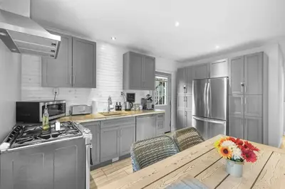 a kitchen with stainless steel appliances and a wooden table at 2BR Downtown Retreat Mins to Beach BBQ and Firepit in Cobourg