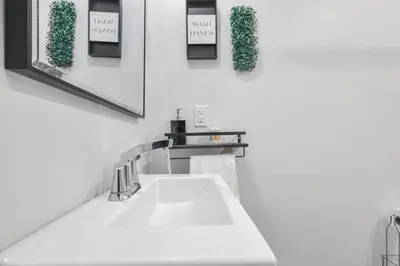 a white sink in a bathroom with two pictures on the wall at 2BR Downtown Retreat Mins to Beach BBQ and Firepit in Cobourg