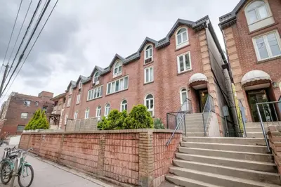 a brick building with stairs in front of it at Cozy 2BR Home with Workspaces, Fireplace and Parking in Toronto