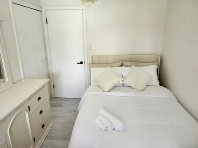 a bedroom with a bed with white sheets and a mirror at 3Q Ltd in Hamilton