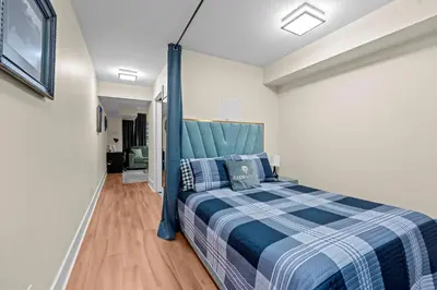 a bedroom with a blue bed with a blue headboard at Classy 1-Bedroom & Den Condo in Heart of Downtown in Toronto