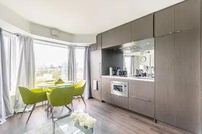 a kitchen with a table and green chairs in a room at Forest 1Bd & DEN in Yorkville 10 Floor in Toronto