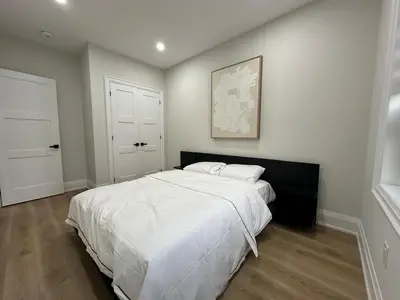 a bedroom with a large bed with white sheets at Mins from Toronto Downtown UFT Exhibition Place in Toronto