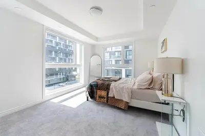 a white bedroom with a bed and two windows at Modern Townhouse Rooftop Vibes in Oakville