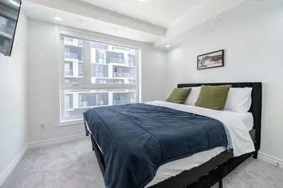 a bedroom with a large bed and a window at Modern Townhouse Rooftop Vibes in Oakville