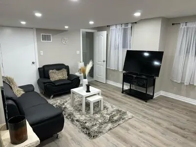 a living room with a couch and a flat screen tv at Cozy 1 Bedroom Apartment in Brampton