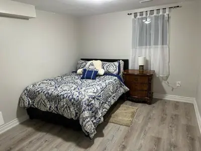 a bedroom with a bed and a dresser and a window at Cozy 1 Bedroom Apartment in Brampton