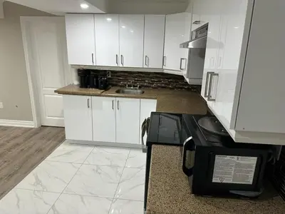 a kitchen with white cabinets and a stove at Cozy 1 Bedroom Apartment in Brampton