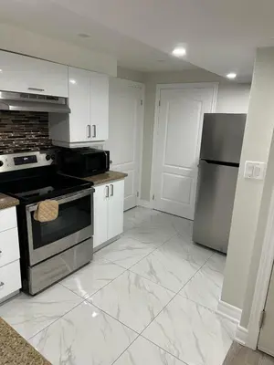 a kitchen with white cabinets and a stove and refrigerator at Cozy 1 Bedroom Apartment in Brampton