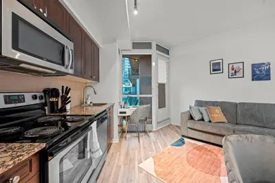 a kitchen and living room with a couch and a stove at Superior 1Bd & DEN Apartment with Balcony in Toronto