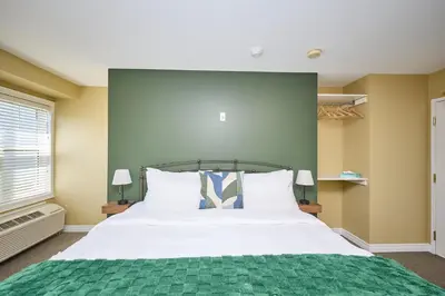 a bedroom with a large bed with a green wall at Nine Vines Hotel in Niagara on the Lake