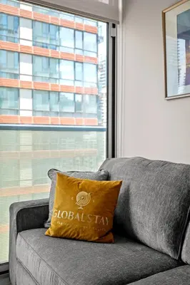 a grey couch with a yellow pillow sitting next to a window at Bright 1BD & Den in Downtown Toronto in Toronto
