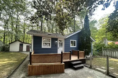 a small blue tiny house with a porch at Lazy Daze (House 2) in Wasaga Beach