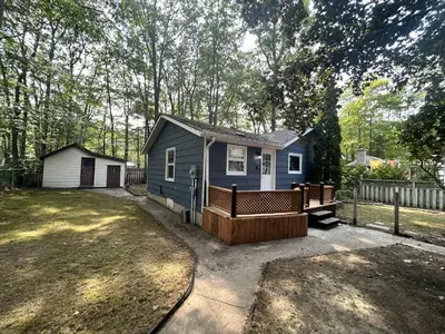 a small blue house with a porch in a yard at Lazy Daze (House 2) in Wasaga Beach