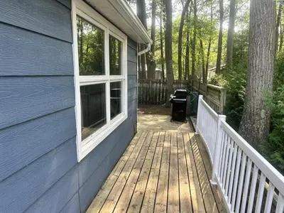 a porch of a blue house with a wooden deck at Lazy Daze (House 2) in Wasaga Beach