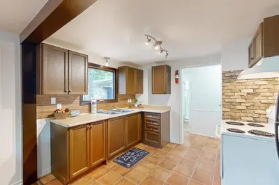a kitchen with wooden cabinets and a brick wall at Lazy Daze (House 2) in Wasaga Beach