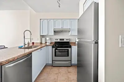 a kitchen with white cabinets and a stainless steel refrigerator at Superior 1Bedroom&DEN Condo with Balcony in Toronto