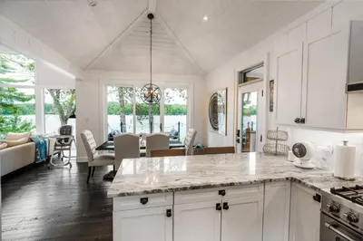 a kitchen with white cabinets and a dining room at Butterfly Lake House | Cozy & Peaceful Stay in Port Carling