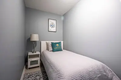 a bedroom with a white bed and a night stand at Panoramic Lake View 1 Bedroom plus Den Condo Iceboat Terrace Downtown Toronto in Toronto