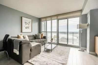 a living room with a couch and a large window at Panoramic Lake View 1 Bedroom plus Den Condo Iceboat Terrace Downtown Toronto in Toronto