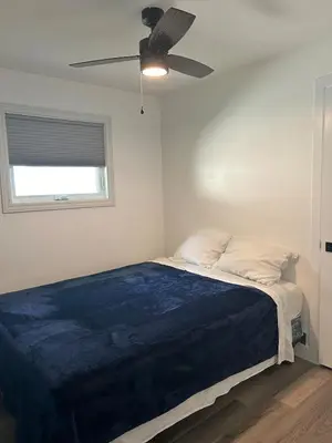 a bedroom with a bed with a ceiling fan at Water Front Cottage - Balsam Lake in Victoria Road
