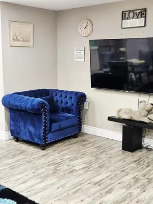 a blue couch in a living room with a clock at Beautiful 3 bedrooms, 2 bathrooms, 4 beds sleep 8, basement close to Falls in Niagara Falls