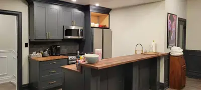 a kitchen with black cabinets and a wooden counter top at Modern Loft with Immersive Theatre Experience in Milton