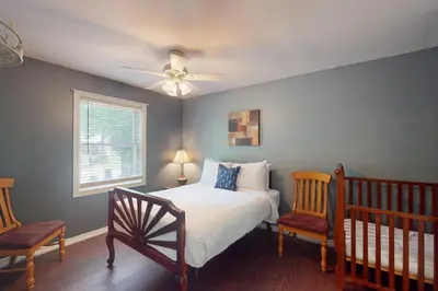 a bedroom with a bed and two chairs and a ceiling fan at Wavy Daze Master in Wasaga Beach